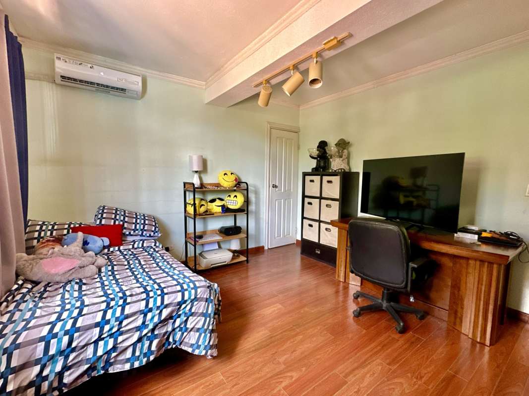 Bedroom with hardwood floors, workspace desk built-in shelves in Las Cumbres private villa Panama