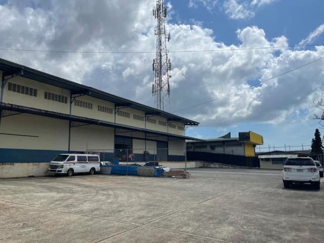 Warehouse exterior with security fencing, parking, and telecom tower in El Crisol Panama