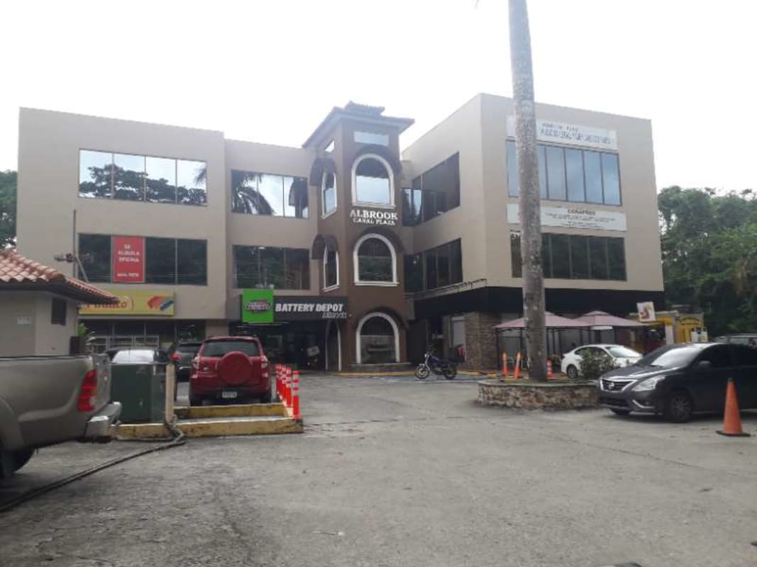 Modern three-story commercial building with parking lot and large reflective windows in Albrook Panama