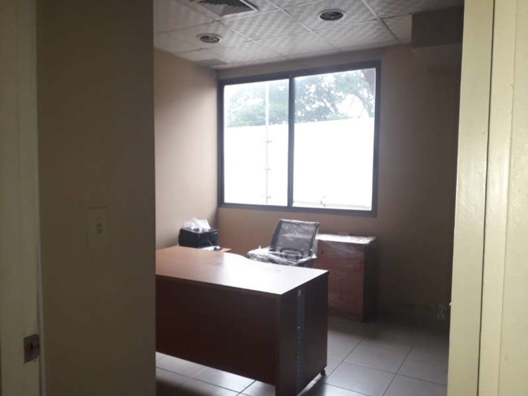 Small private office with wooden desk, chair, cabinet and large window in Albrook Panama
