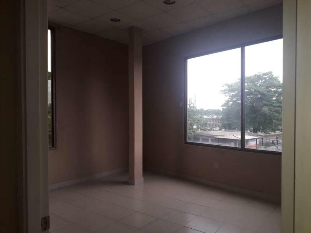 Empty open-plan office with tiled floor, ceiling tiles and natural daylight in Albrook Panama