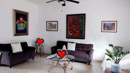 Modern living room with large windows, dark sofas, ceiling fan in Panama Pacifico Howard house