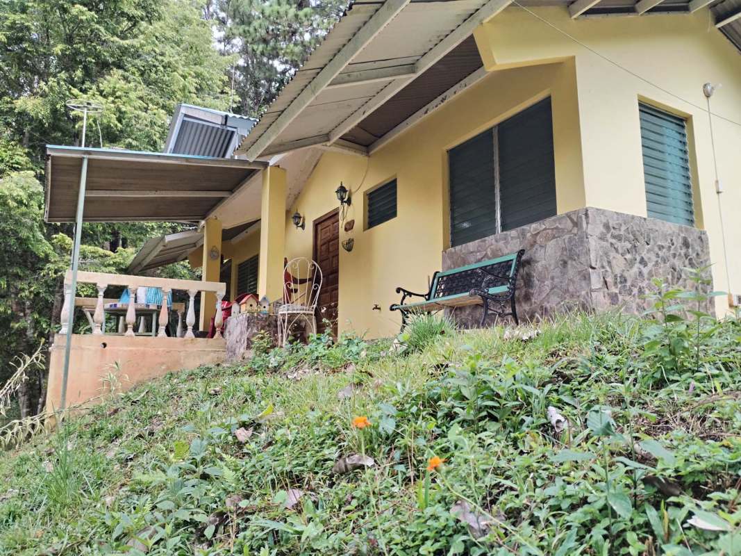 Rustic yellow house exterior with stone accents and large garden surrounded by forest Cerro Azul Panama