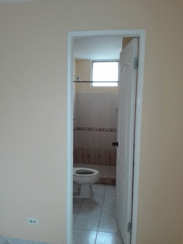 Small bathroom with beige tiles, white toilet and small window PH Villa de las Fuentes Tumba Muerto Panama