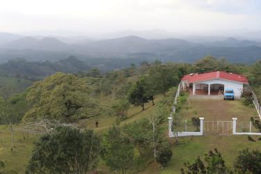 Hilltop rustic red roof house fenced land surrounded by valley mountain scenery in La Pintada Coclé Panama