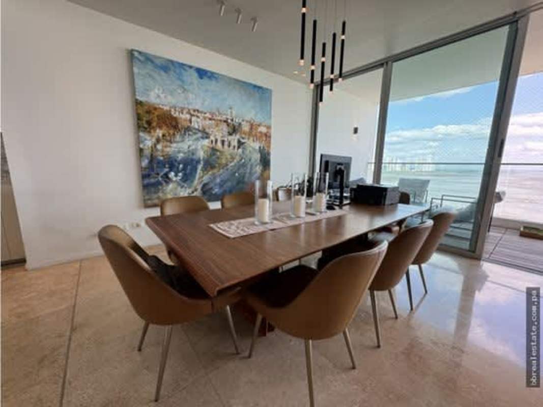 Contemporary dining area with glass balcony doors and city skyline backdrop at PH Ocean Sky Panama City