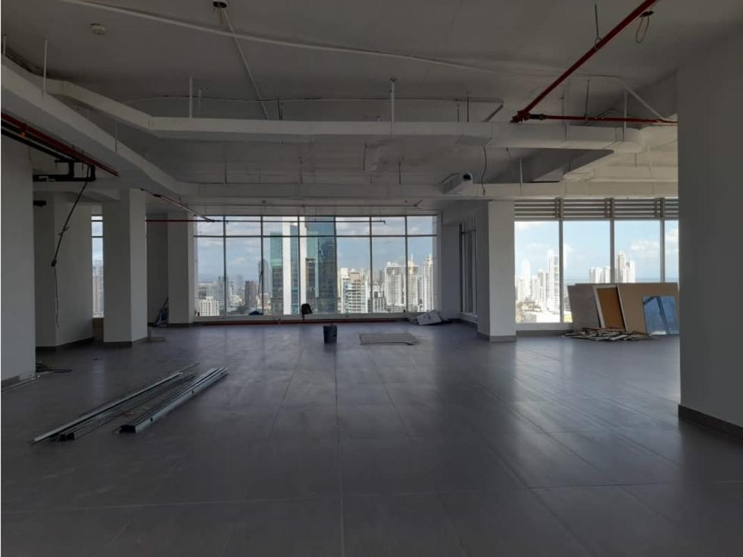 Open commercial space with exposed ceiling pipes and floor-to-ceiling windows overlooking city skyline in PH Panama Design Center Obarrio