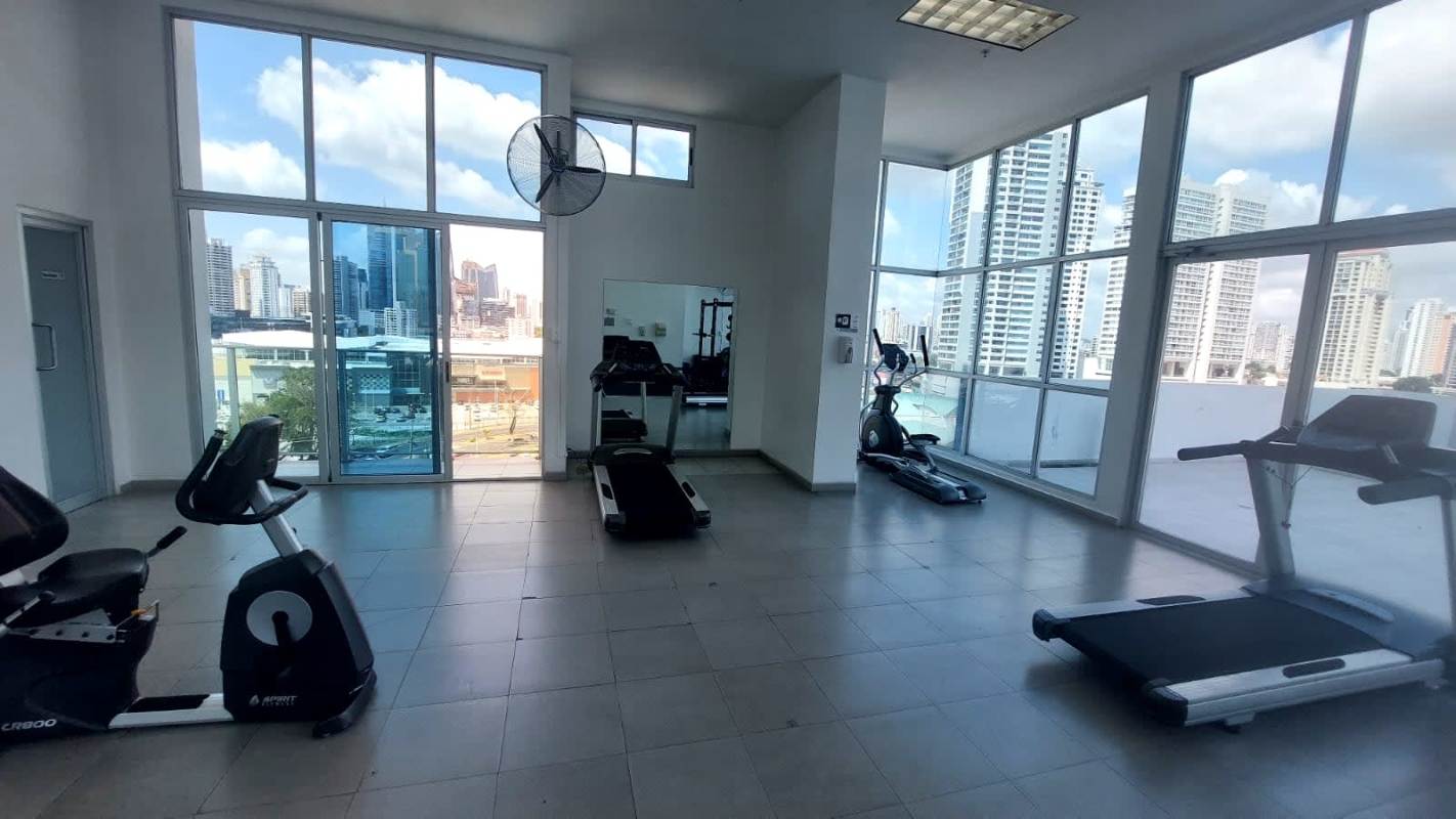 Full gym with cardio equipment and panoramic windows overlooking ocean at PH Marina Plaza Panama City