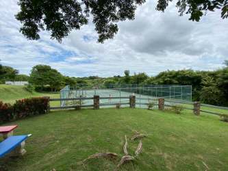 Outdoor private tennis court surrounded by lush greenery inside Punta Barco Village Panama