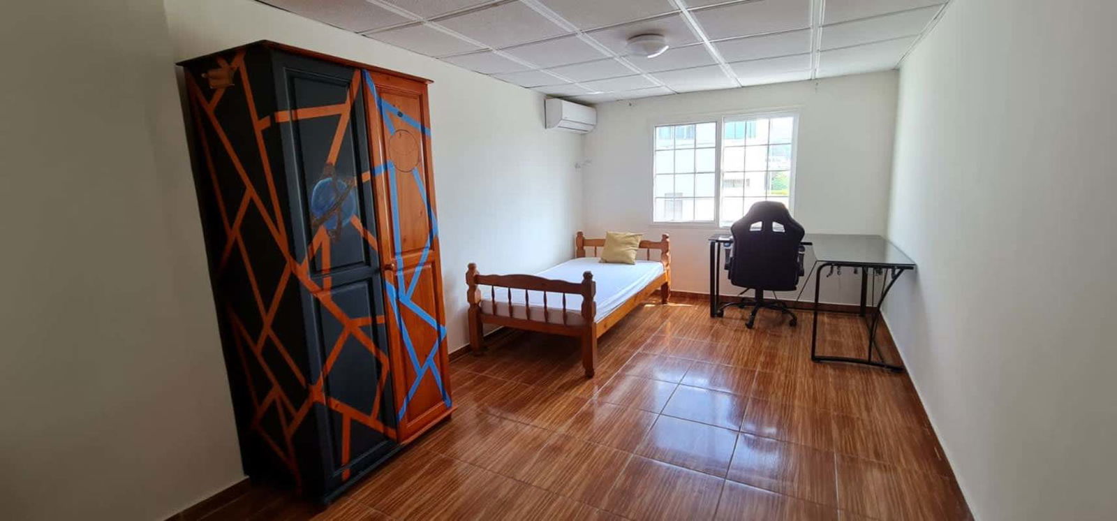Minimalist bedroom with bed, large window, wooden wardrobe, tile floors in Altavista Panama City