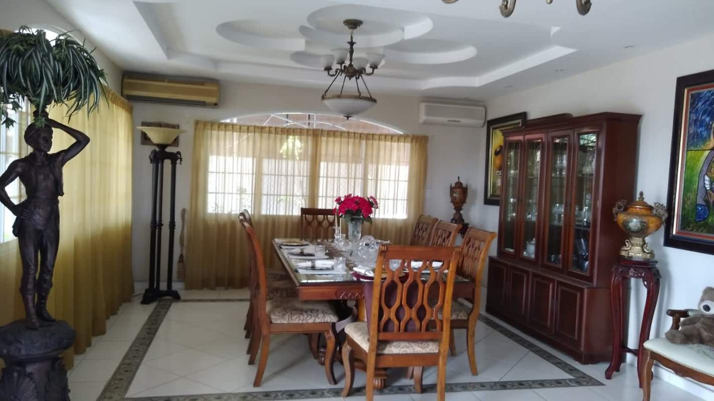 Sunny balcony terrace with white balustrade, outdoor dining set, potted plants and skyline views in Bethania Panama