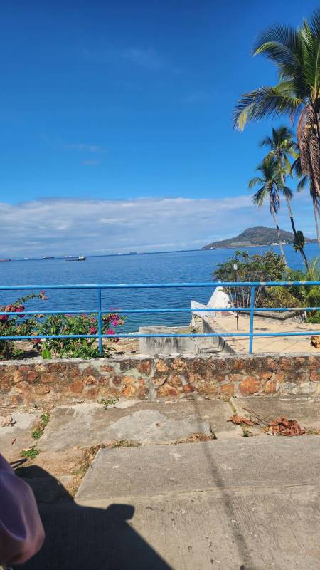 Stone wall, lush flowers and blue ocean railing at Taboga Panama waterfront