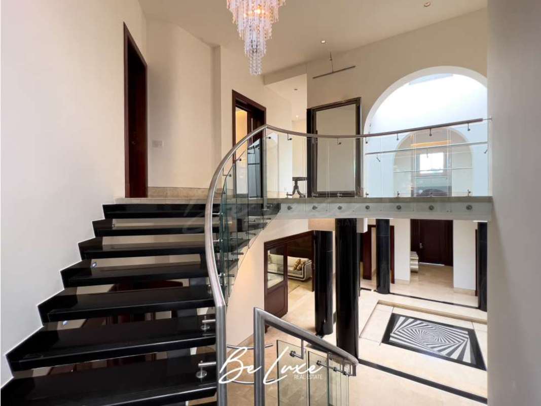 Double-height foyer with marble floors and elegant curved staircase in luxury mansion Costa del Este Panama