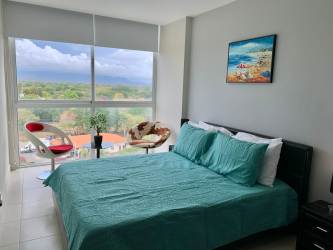 Bedroom with turquoise bedding, large panoramic window and mountain view in PH Ibiza Coronado Panama