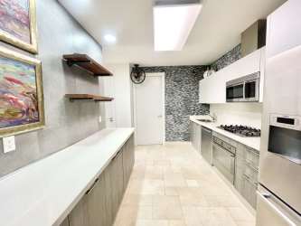 Contemporary kitchen with stainless steel appliances open shelving and tile backsplash in beachfront loft