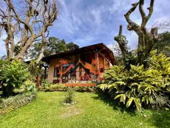 Exterior of rustic Panama house with lush garden and mountain backdrop in Valle de Antón