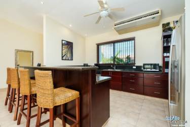 Spacious kitchen with granite island, dark wood cabinets and appliances in Coronado golf home