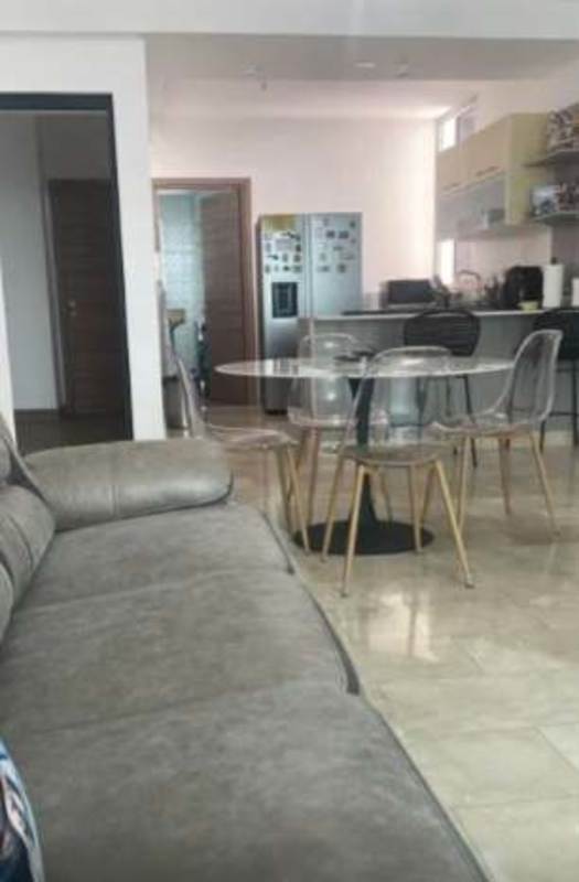 Open-plan living room and kitchen with glass dining table and modern appliances PH Dynasty Residences Panama City