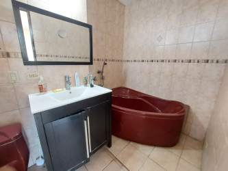 Bathroom with beige tiles corner bathtub and black vanity cabinet in Guadalupe La Chorrera Panama