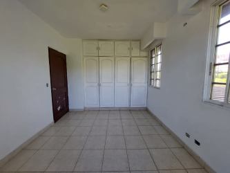 Minimal bedroom with white walls built-in closet tiled floor and windows house in La Chorrera