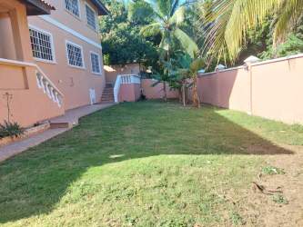 Backyard with tropical plants lawn and peach colored wall in Guadalupe La Chorrera