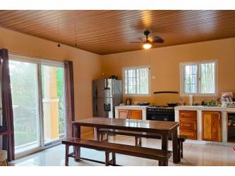 Open kitchen and dining area with wood ceiling, porch access in mountain home Altos del María Panama