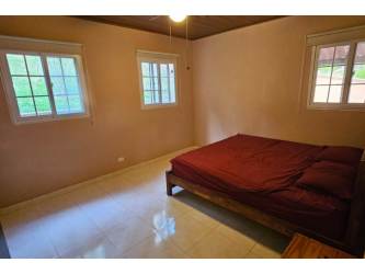Bedroom with windows, mountain scenery, ceiling fan and natural light in Altos del María mountain house Panama