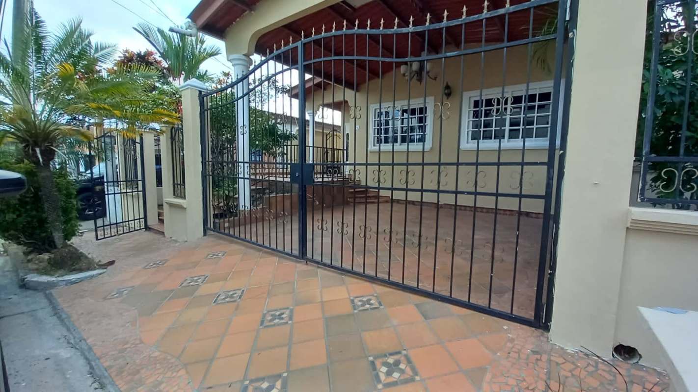 Covered carport and landscaped front with palm trees in Brisas del Golf