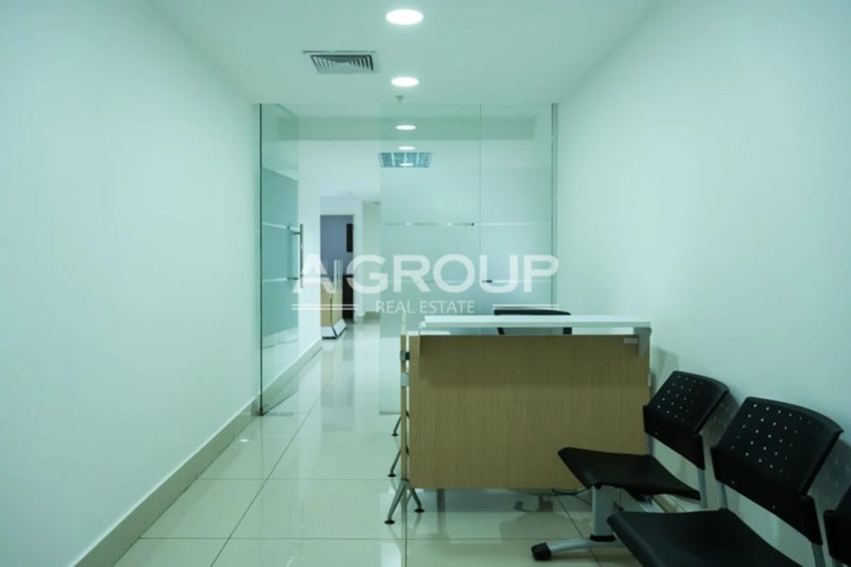 Reception area with glass walls, wood desk, chairs at BICSA Tower office for rent