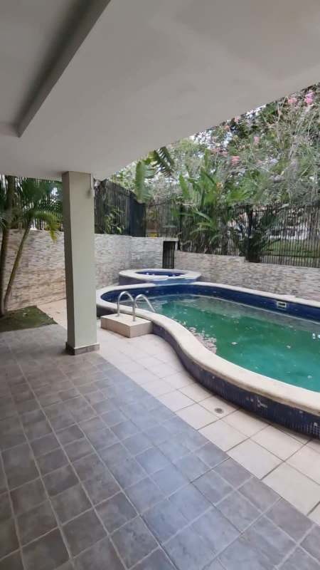 Large private swimming pool with spa surrounded by stone patio and greenery in stylish Panama City residence