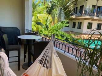 Balcony with hammock and seating overlooks tropical gardens and pool in Buenaventura Panama luxury resort