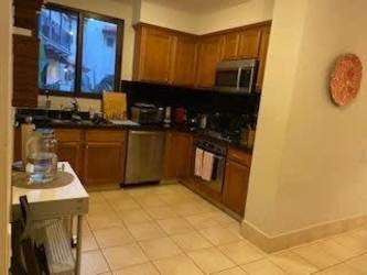 Modern kitchen with wooden cabinetry, black backsplash and stainless appliances in Paseo de la Casa Buenaventura