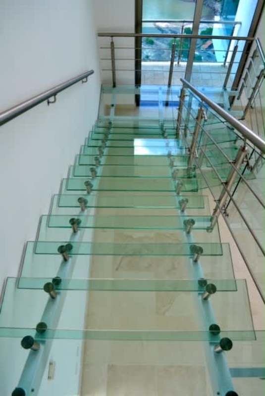 Floating glass staircase with metal railing connecting penthouse levels in PH Aqualina
