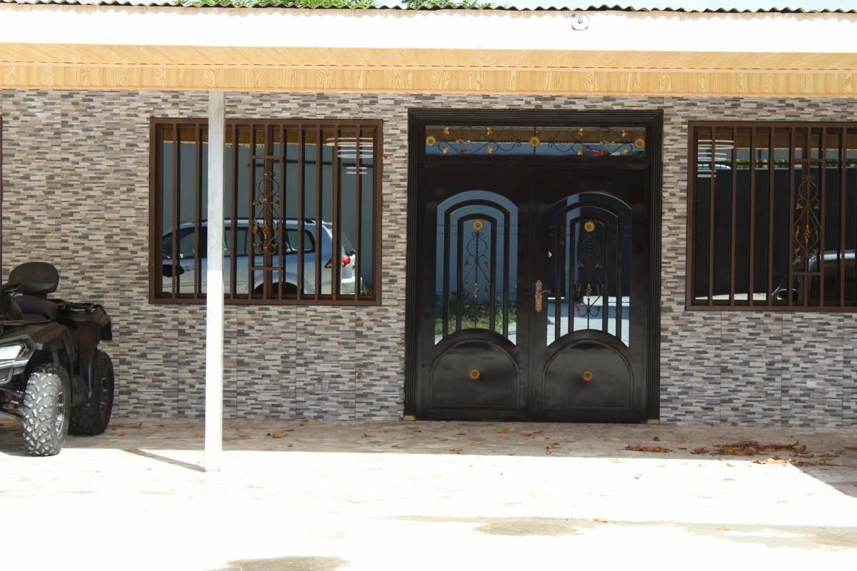 House facade with electric gate, stone veneer finish, and barred windows Villa Zaita Panama