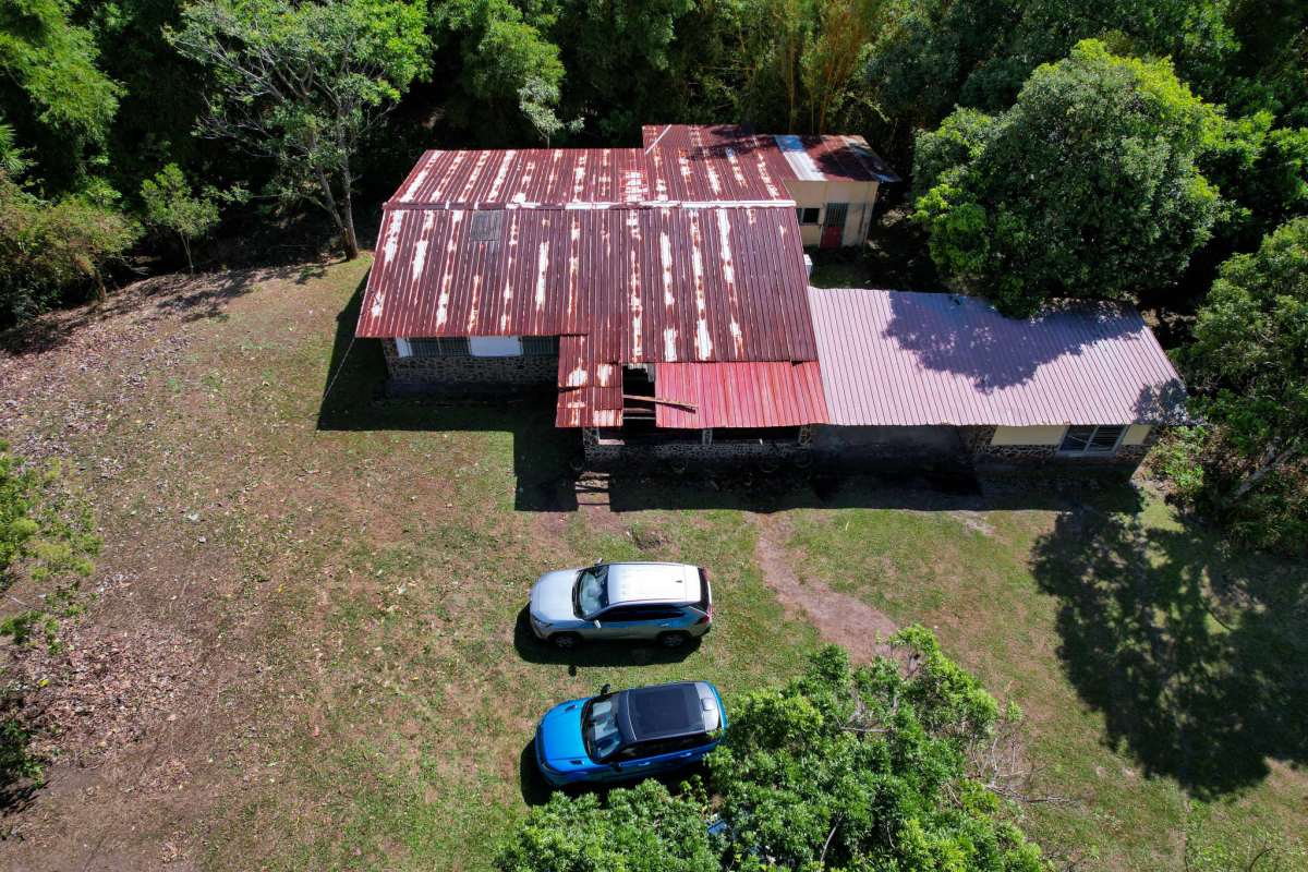 Overhead view rustic mountain house metal roof cars grassy yard El Valle de Anton Panama