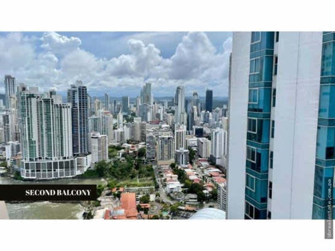 Luxurious bedroom with large upholstered bed, panoramic glass windows, and partial ocean view at PH The Ocean Club Punta Pacifica