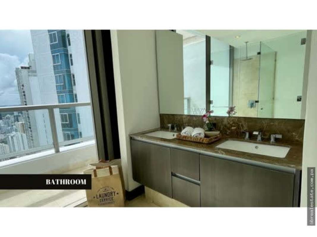 Modern bathroom with double sink, marble counters, large mirror and skyline view at PH The Ocean Club