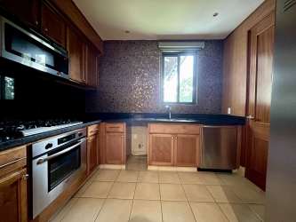 Traditional kitchen with stainless steel appliances, wood cabinetry and stone countertop in beach apartment Buenaventura