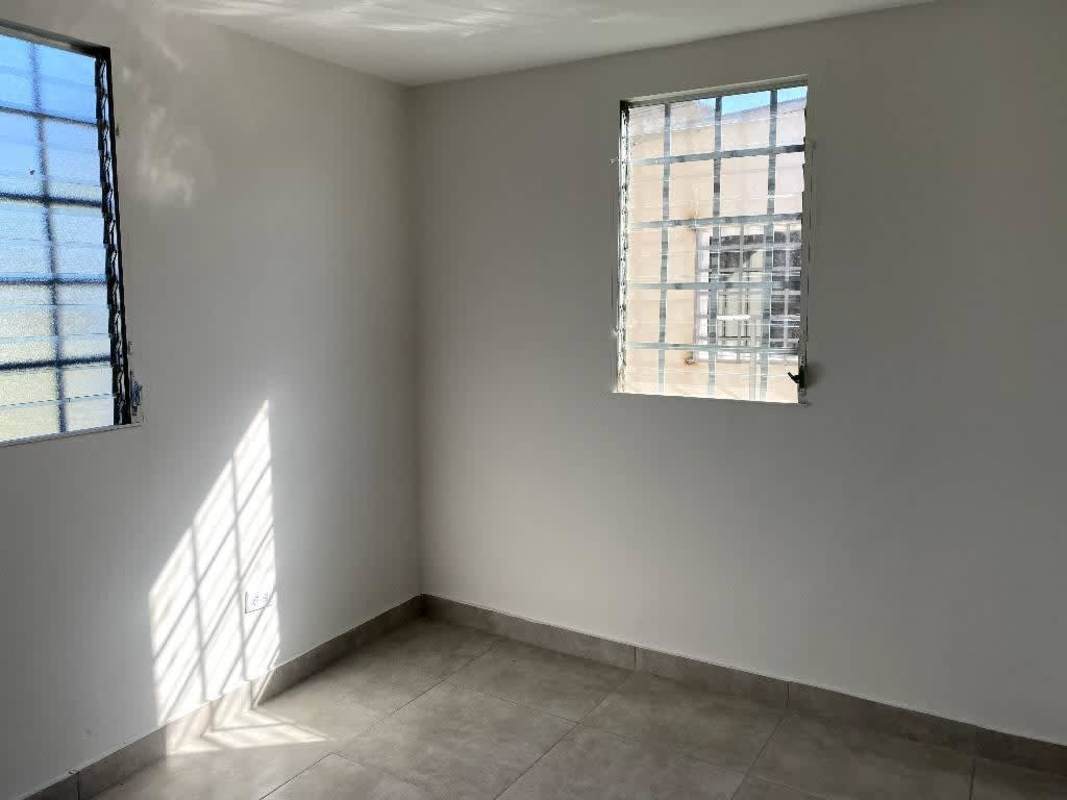 Minimalist bright bedroom with tiled floors and bars on windows Pacora corner house