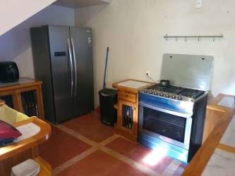 Open concept living dining area with wooden bar, tile floors, large windows at Ocean Lofts Pedasi Panama