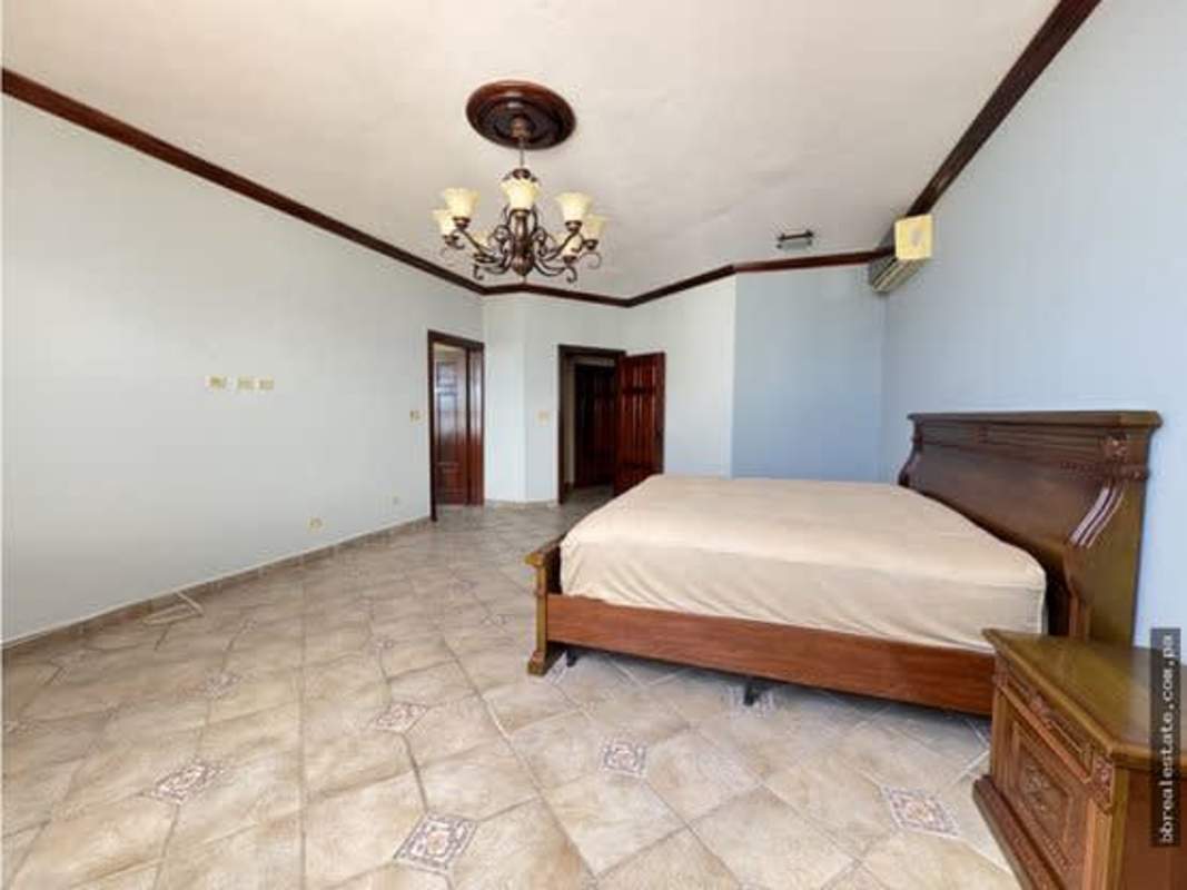 Spacious bedroom with tile floors, chandelier, wood closet doors in PH Vista Park El Carmen Bella Vista Panama