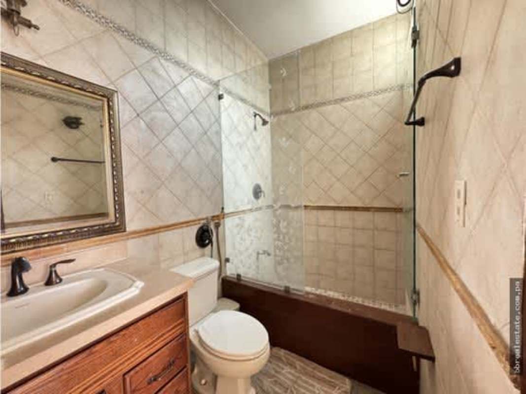 Spacious bathroom with glass-enclosed bathtub, wood vanity, and ceramic tiles in PH Vista Park Panama City