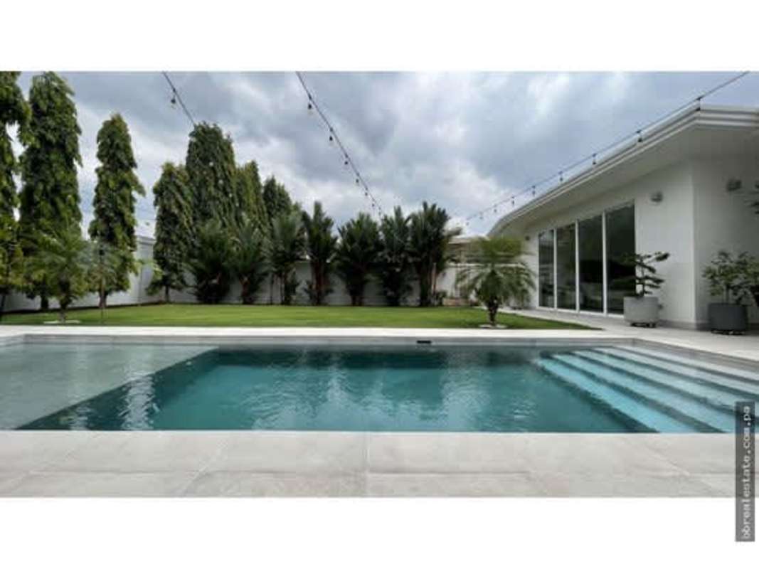 Open plan living room with floor-to-ceiling glass overlooking private pool and garden in Costa Sur Panama