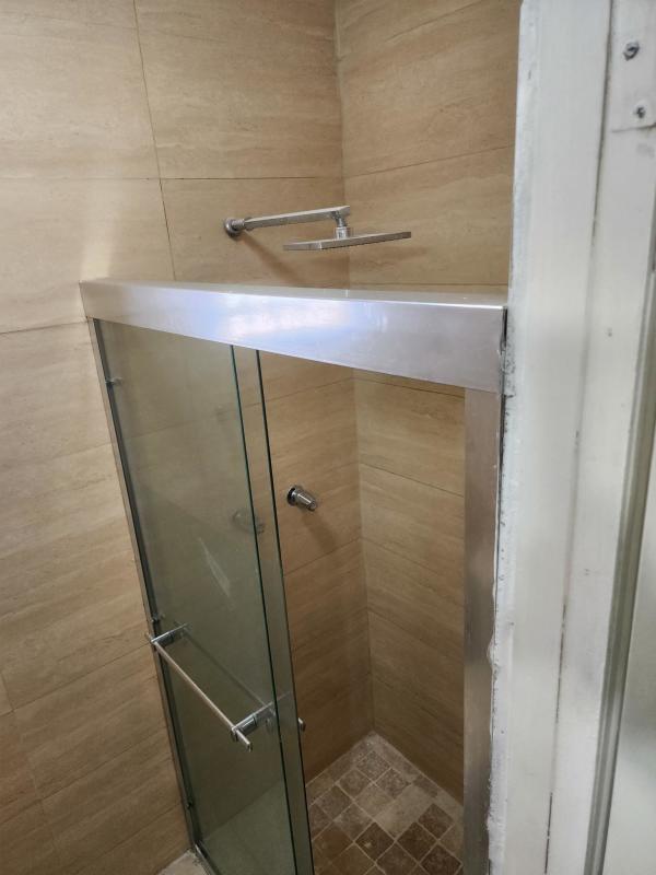Bathroom with glass shower enclosure and beige tiles in updated Los Harinos home Panama City