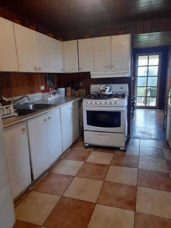 Cozy rustic living room with fireplace, wood ceiling and plaid sofa in Cerro Azul mountain home Panama