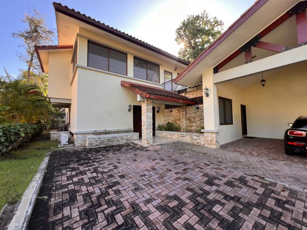 Front of two-story Mediterranean house with arched entry, balcony, and manicured lawn Senderos de Cruces Panama