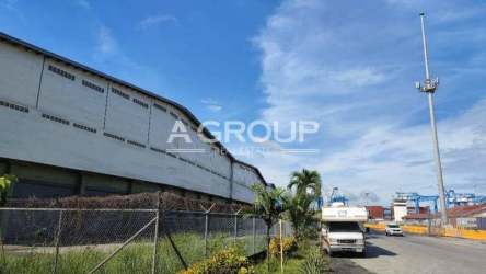 Wide exterior warehouse facility with container trucks along paved road in Colon Free Trade Zone