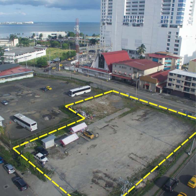 Vacant lot marked in city surrounded by vehicles, adjacent to ocean and skyline background