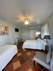 Bright guest room with double beds tile floors ceiling fan air conditioner Casa Amarilla hotel Panama
