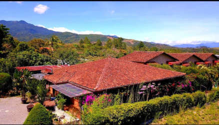 Aerial view with terracotta roofs, mountain backdrop and lush gardens at Boquete boutique hotel for sale